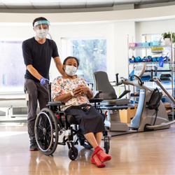 Image of A healthcare worker pushes a woman in a wheelchair in one of the rehabilitation spaces at the Freeport Campus